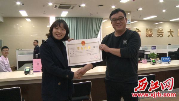 市民孔小姐就从广宁县行政服务中心顺利领取到全县首张2019横版营业执照。通讯员供图