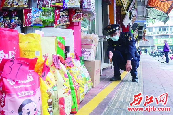 城管执法队员查看店铺是否超过黄线范围。西江日报记者 严炯明 摄
