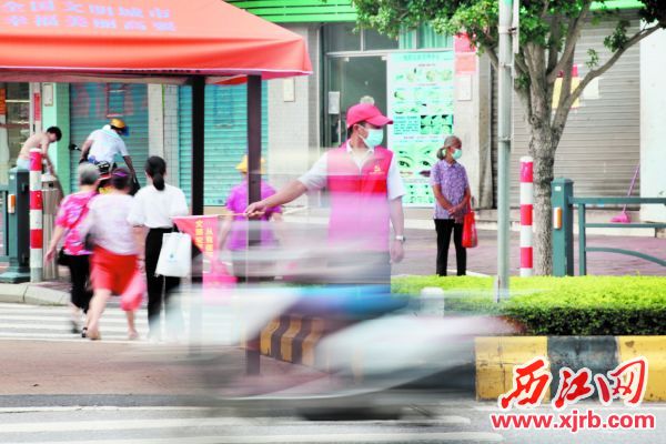 文明交通志愿者在指挥交通。 西江日报记者 杨永新 摄