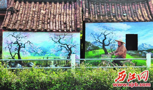 彩色墙绘前村民骑车而过。 西江日报记者 李考考 摄